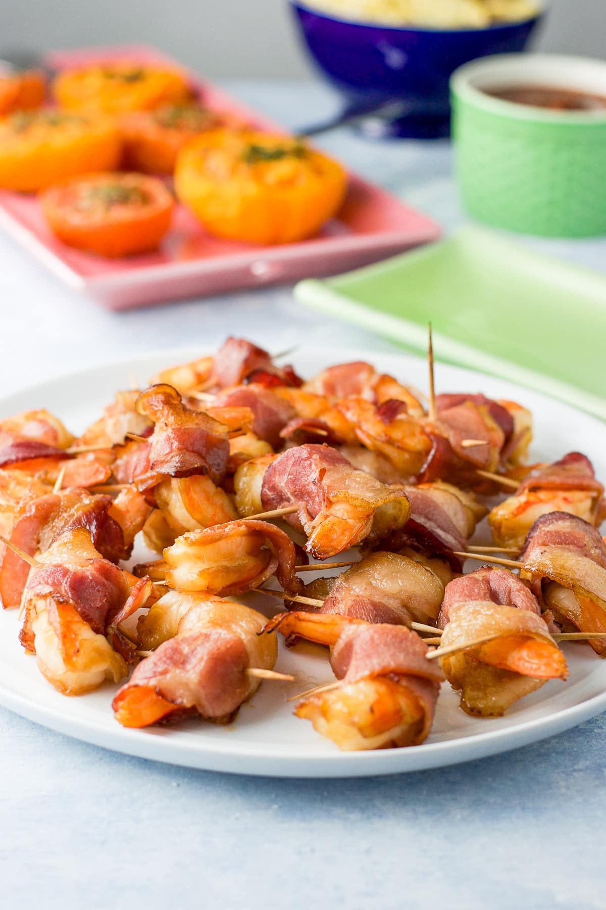 Toothpicks in the shrimp appetizer on the white plate with more appetizers in back