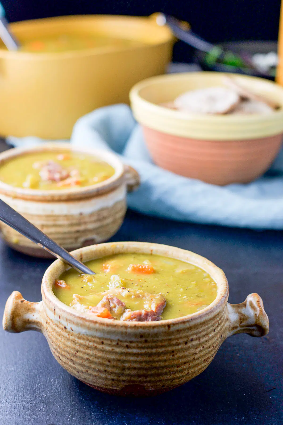two crocks filled with the pea soup with pita and the serving bowl