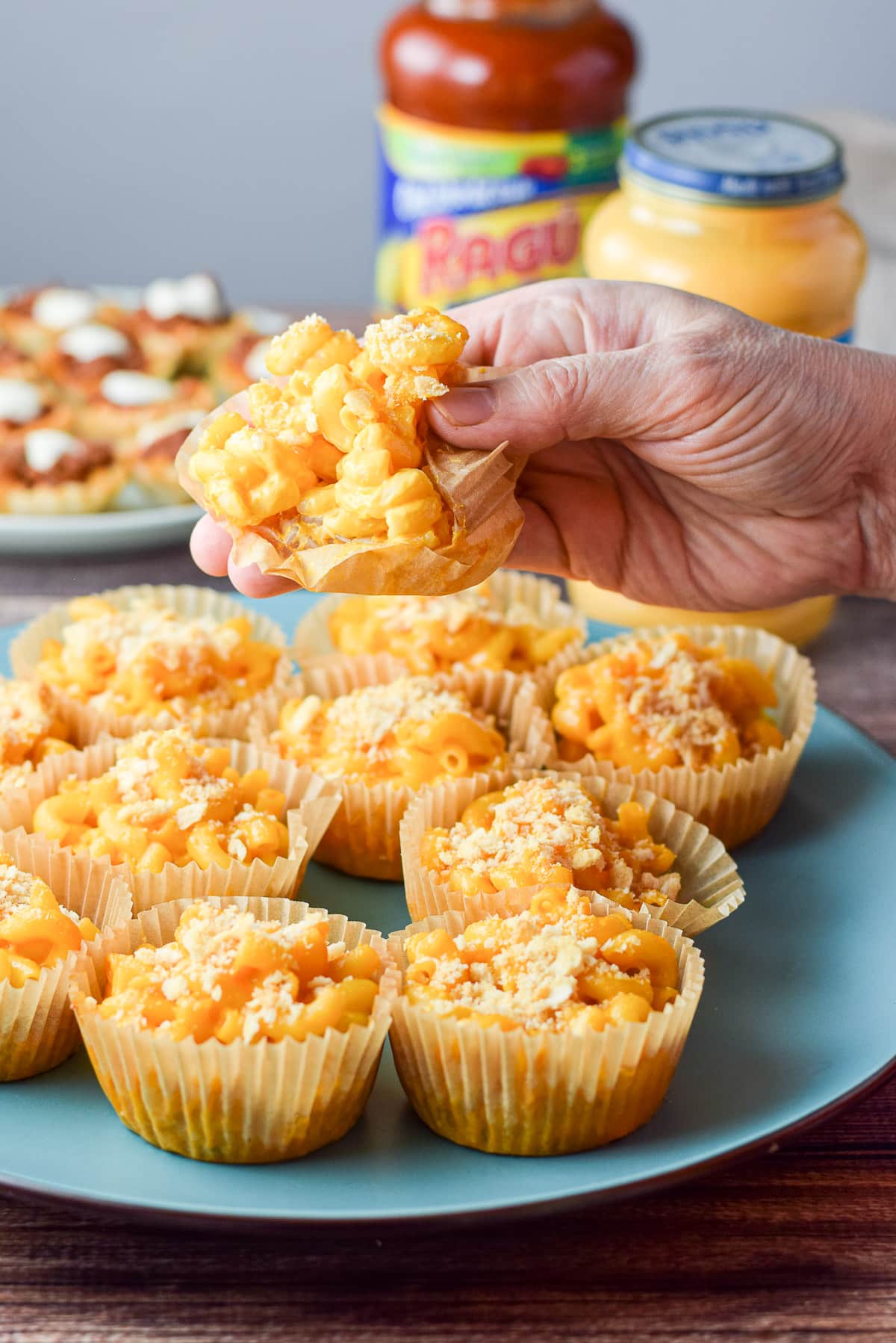A hand holding the mac and cheese appetizer held over the plate
