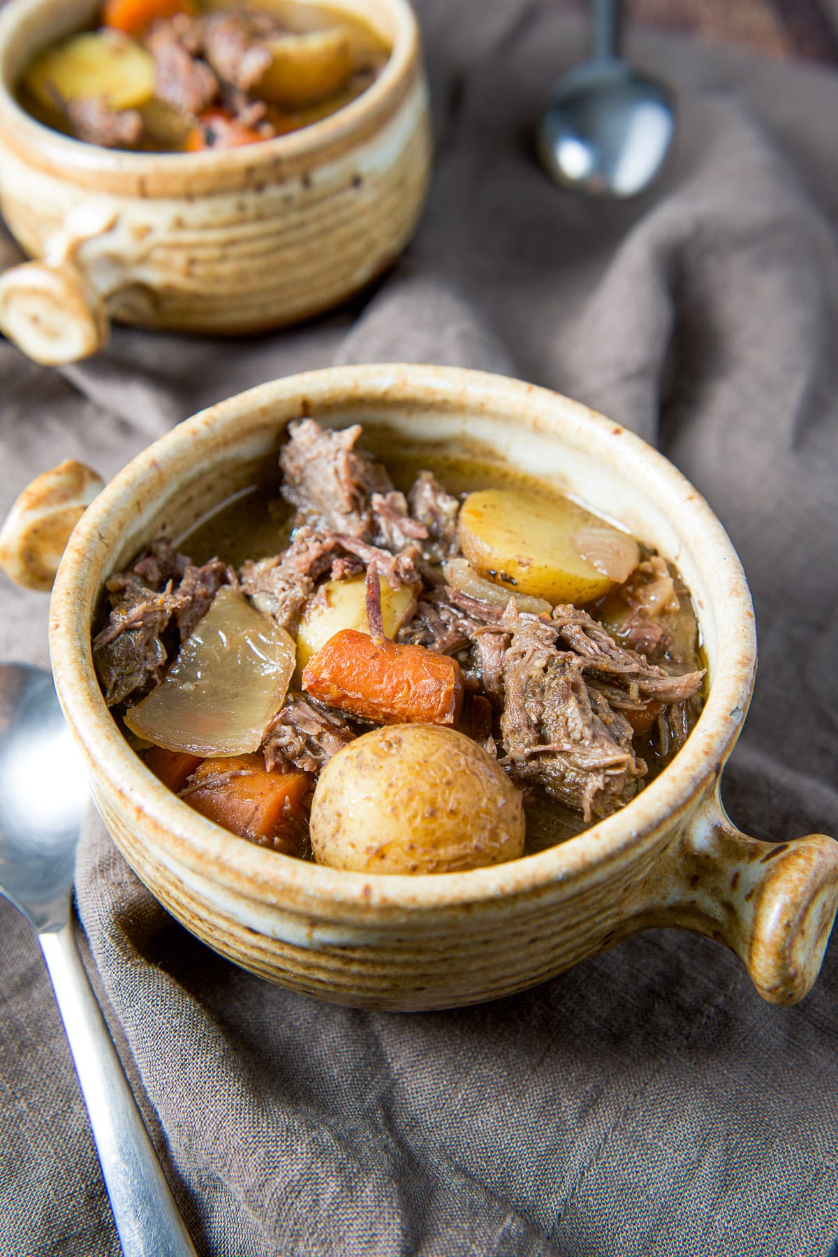 A full crock filled with the chuck roast in front of another