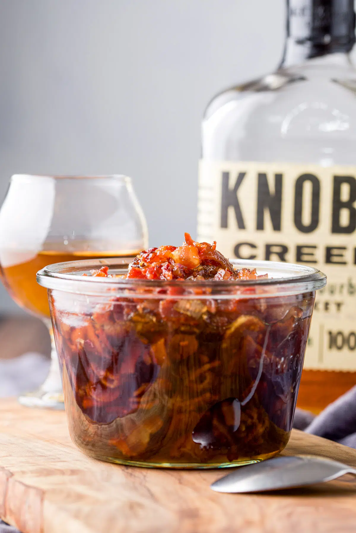 Vertical view of the jar of bacon with bourbon in the back