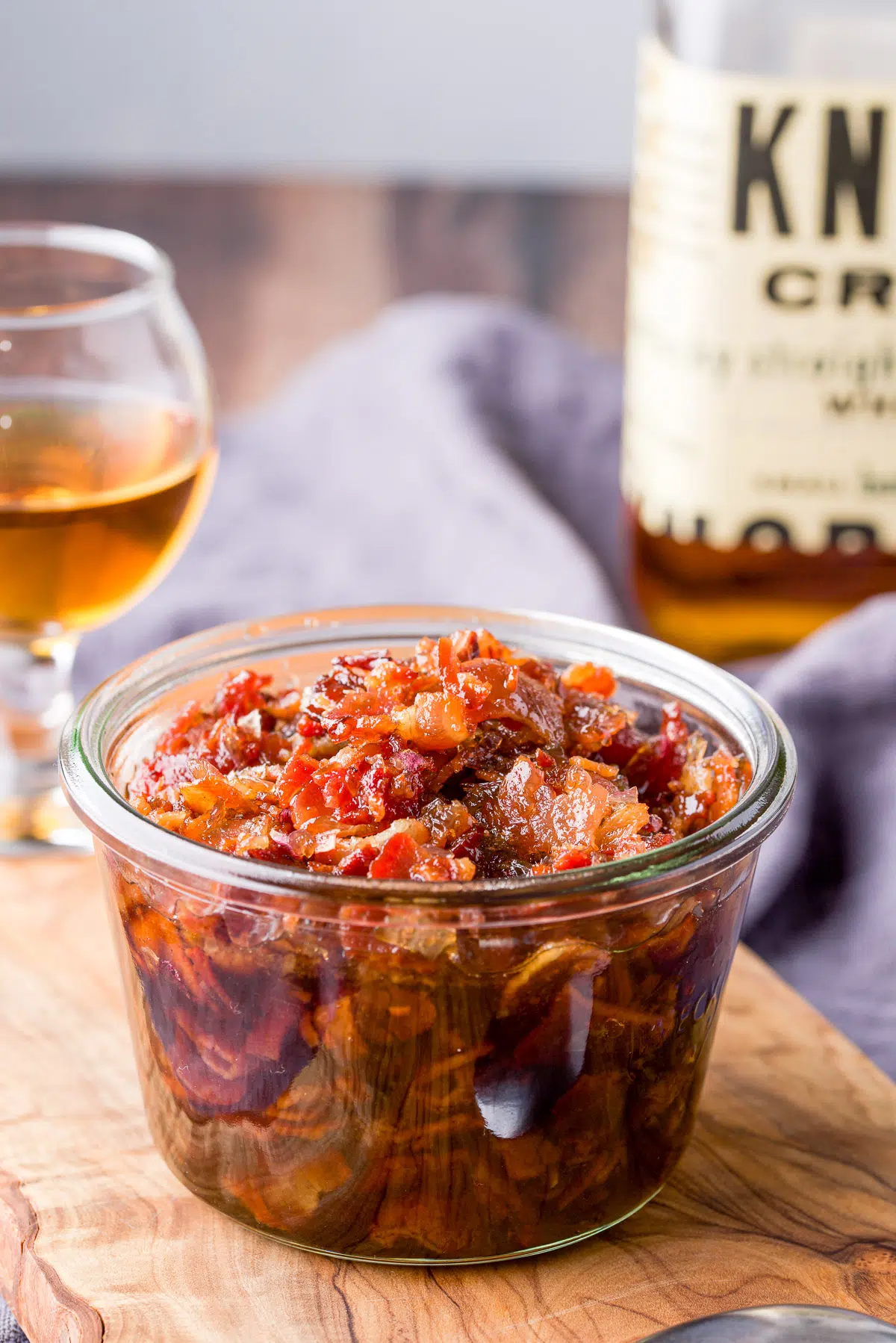 Bourbon in a glass behind the jar of bacon jam