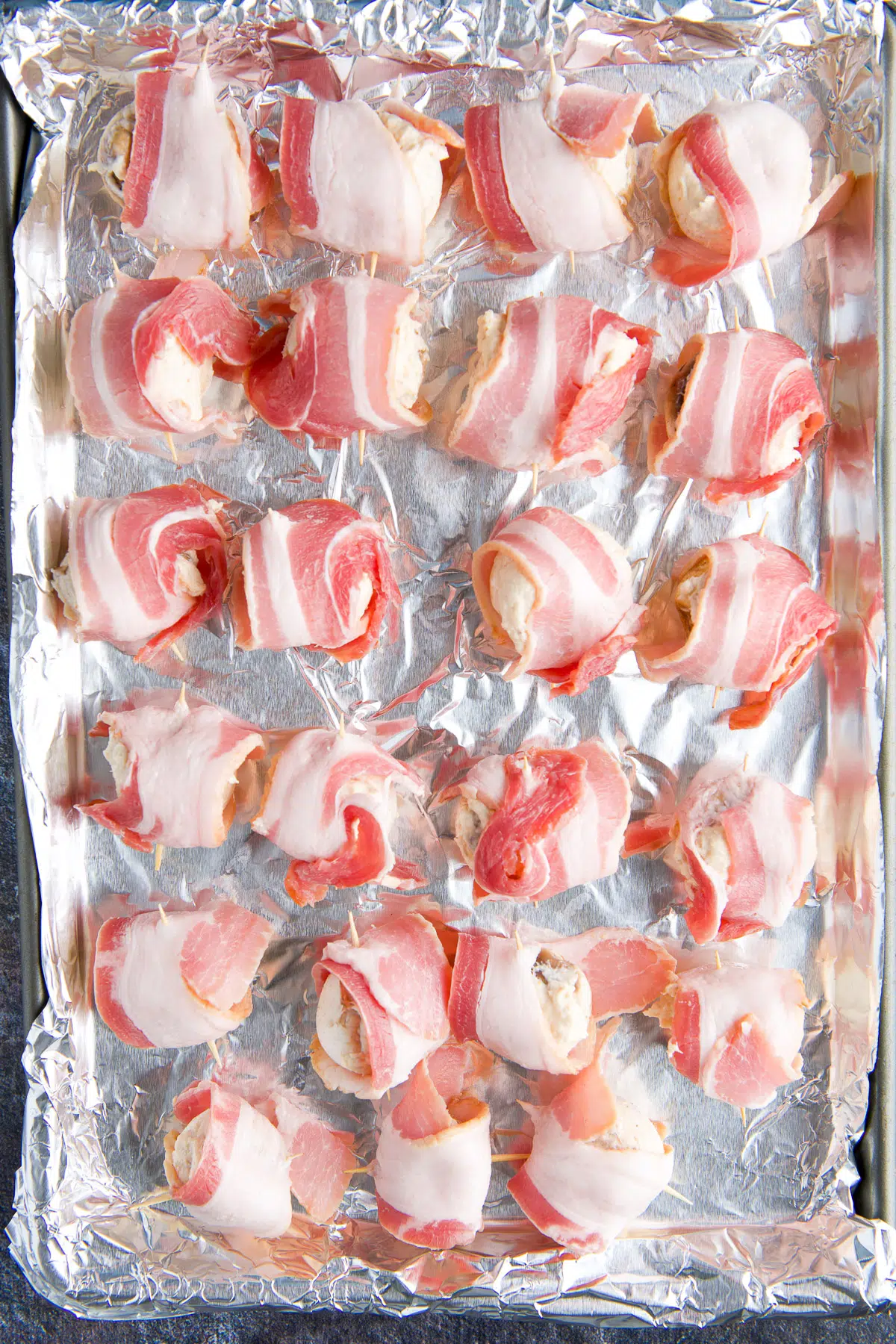 a foil lined pan with bacon wrapped around mushrooms