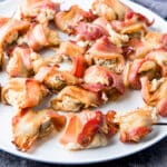 square photo of a plate of stuffed mushrooms in bacon