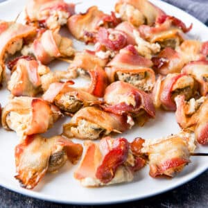 square photo of a plate of stuffed mushrooms in bacon