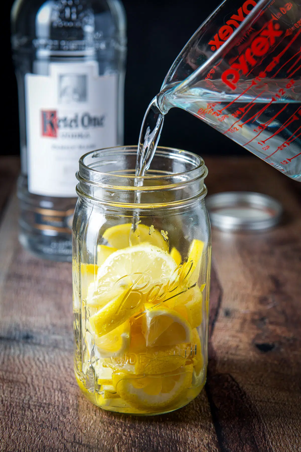Pouring the vodka in the jar with the lemons