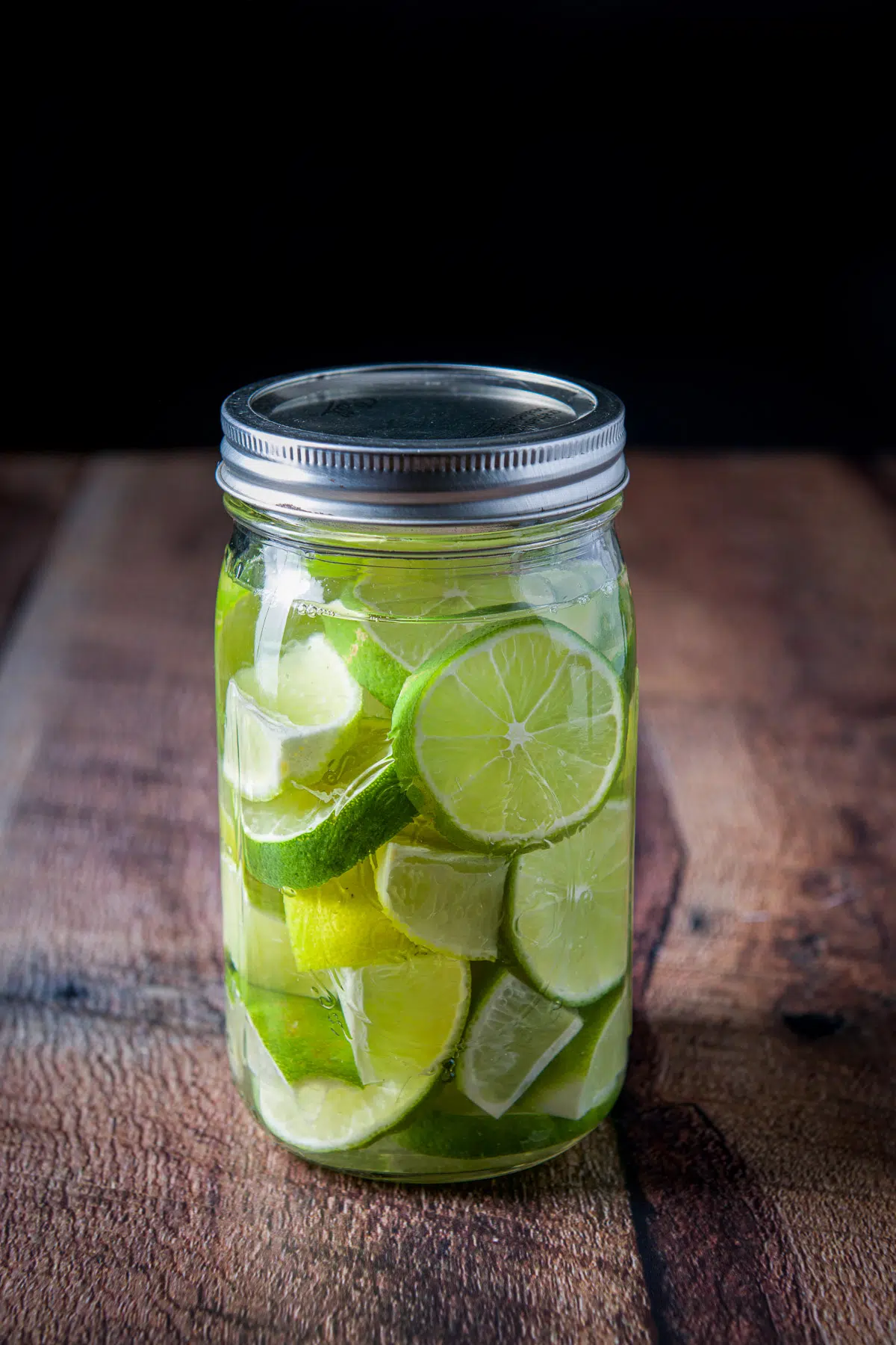 The lid capped on the jar of limes and vodka
