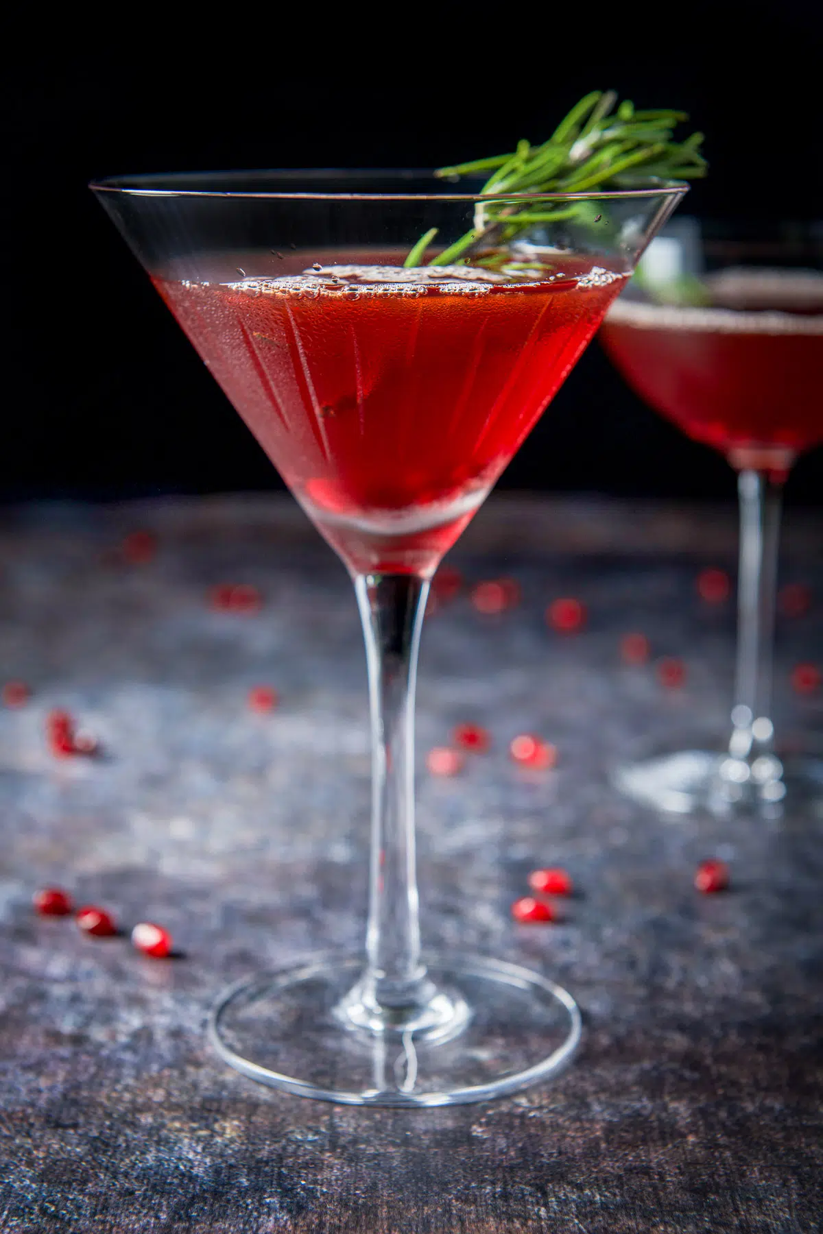 Vertical view of the pomegranate manhattan with rosemary and pom seeds