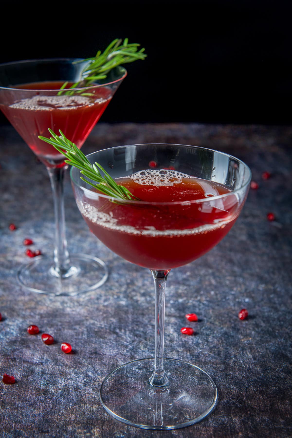 A bowl glass with the cocktail and garnish in it with another glass in the back