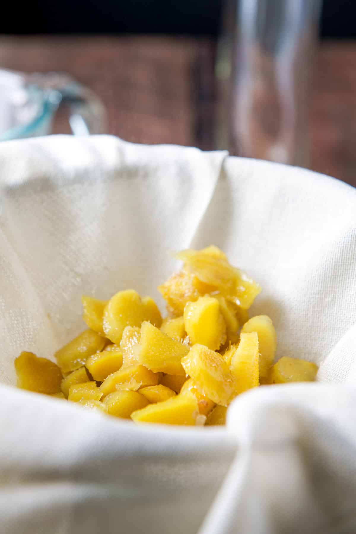 Cooked ginger in a cheesecloth covered sieve