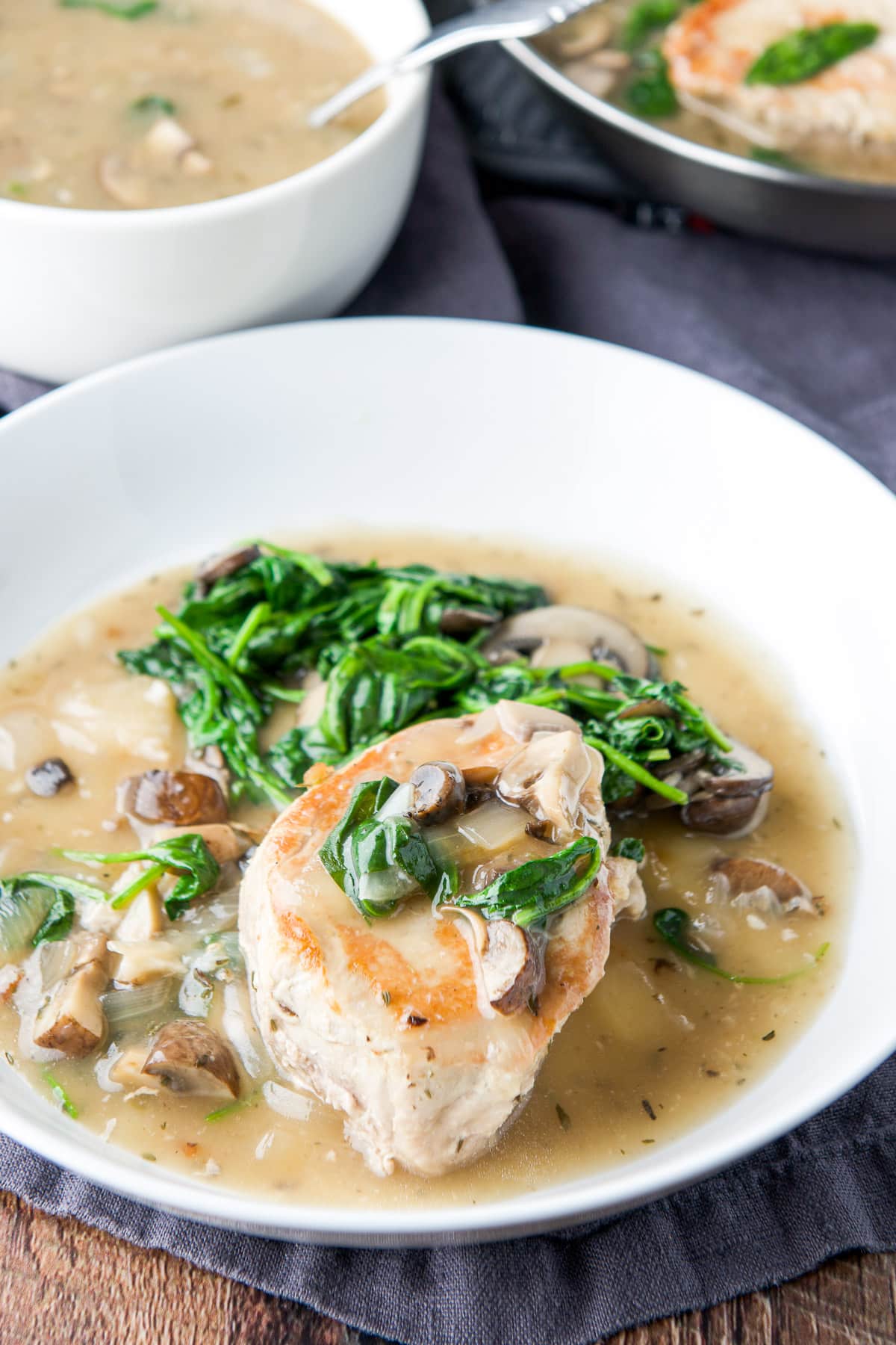 Vegetables and broth in a bowl with a seared pork chop