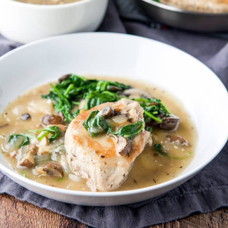 a pork chop with vegetables and broth in a deep dish - square