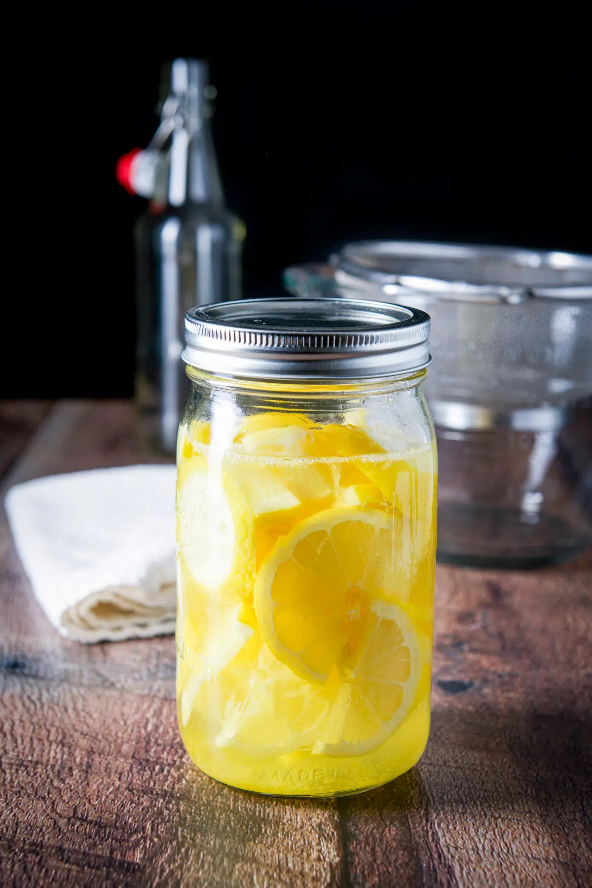 Jar with the lemons in the vodka with a sieve in the back