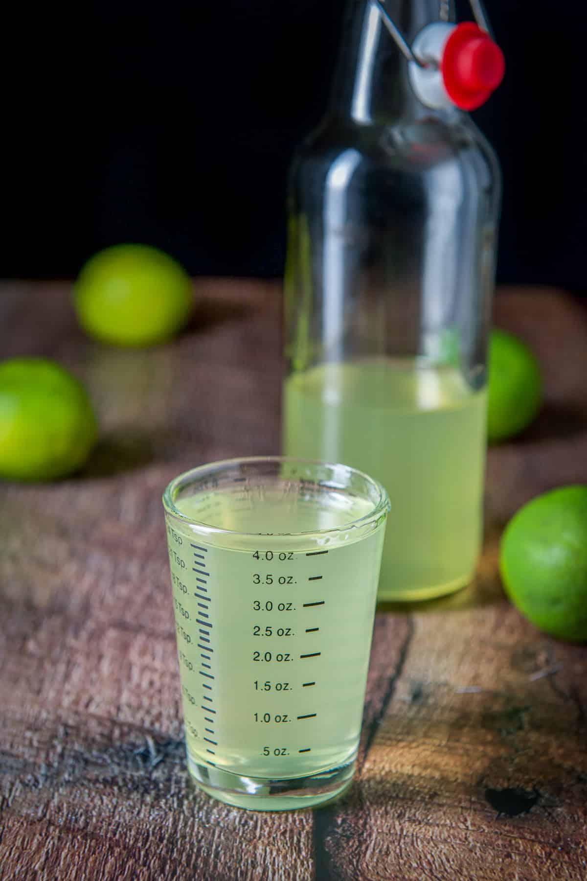 A bottle in the back with the measuring glass filled with the vodka