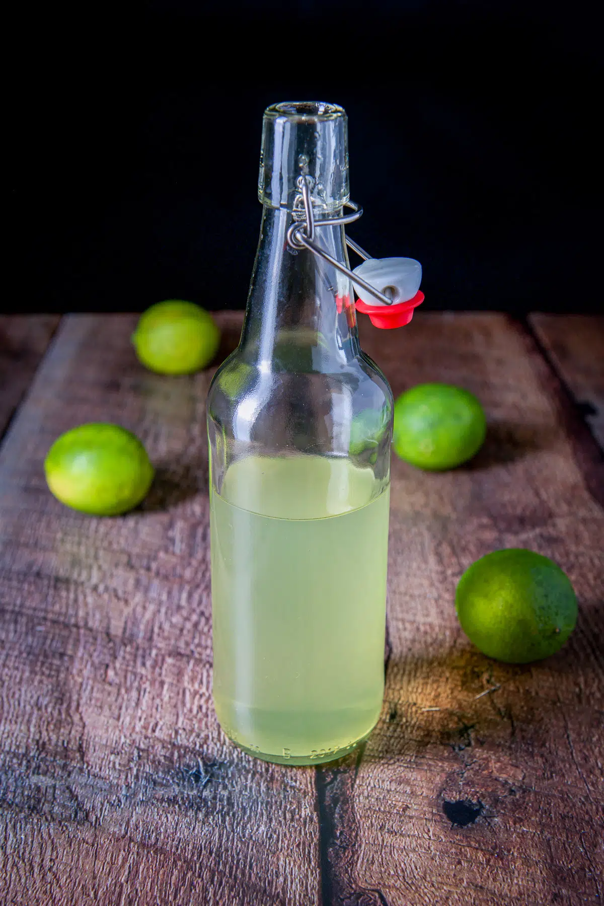 A bottle with the lime vodka with limes in the back