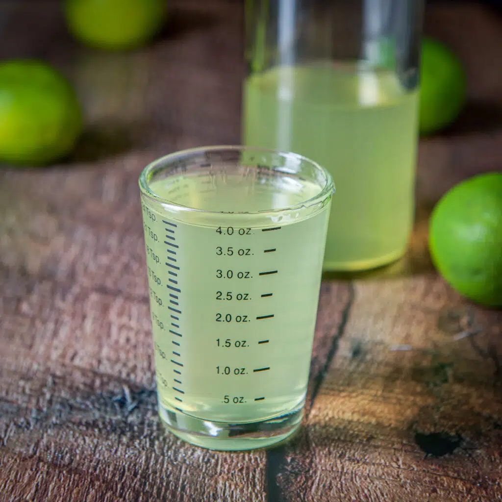 Lime vodka measured out with the bottle behind - square