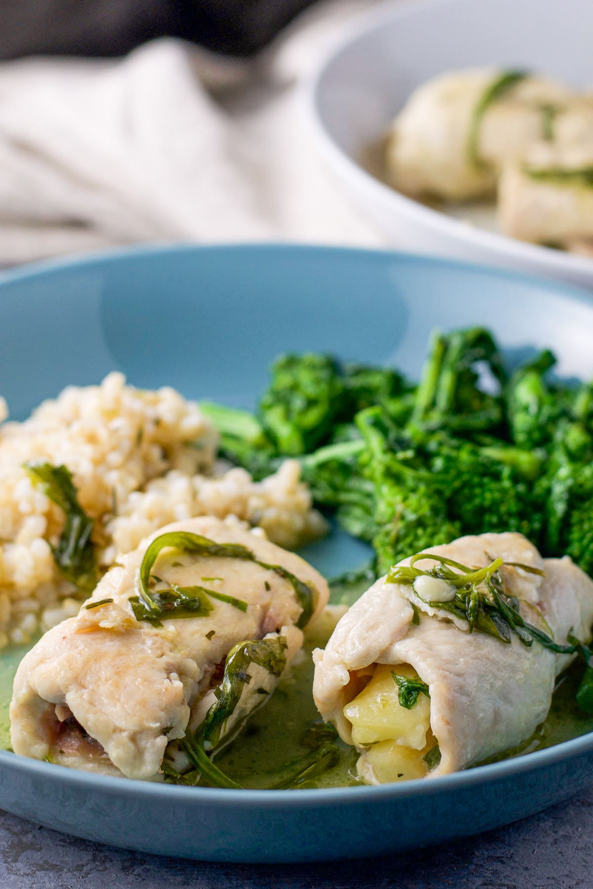 A blue plate with two chicken saltimbocca pieces on it