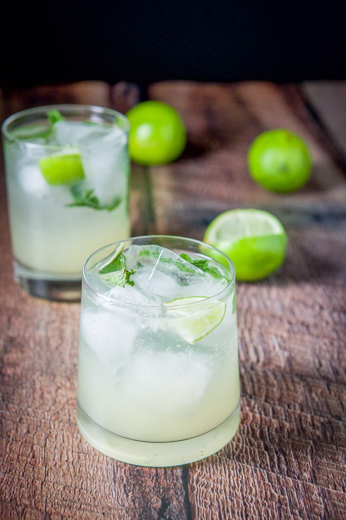 Lime wedges in the mojitos with mint and some limes on the table