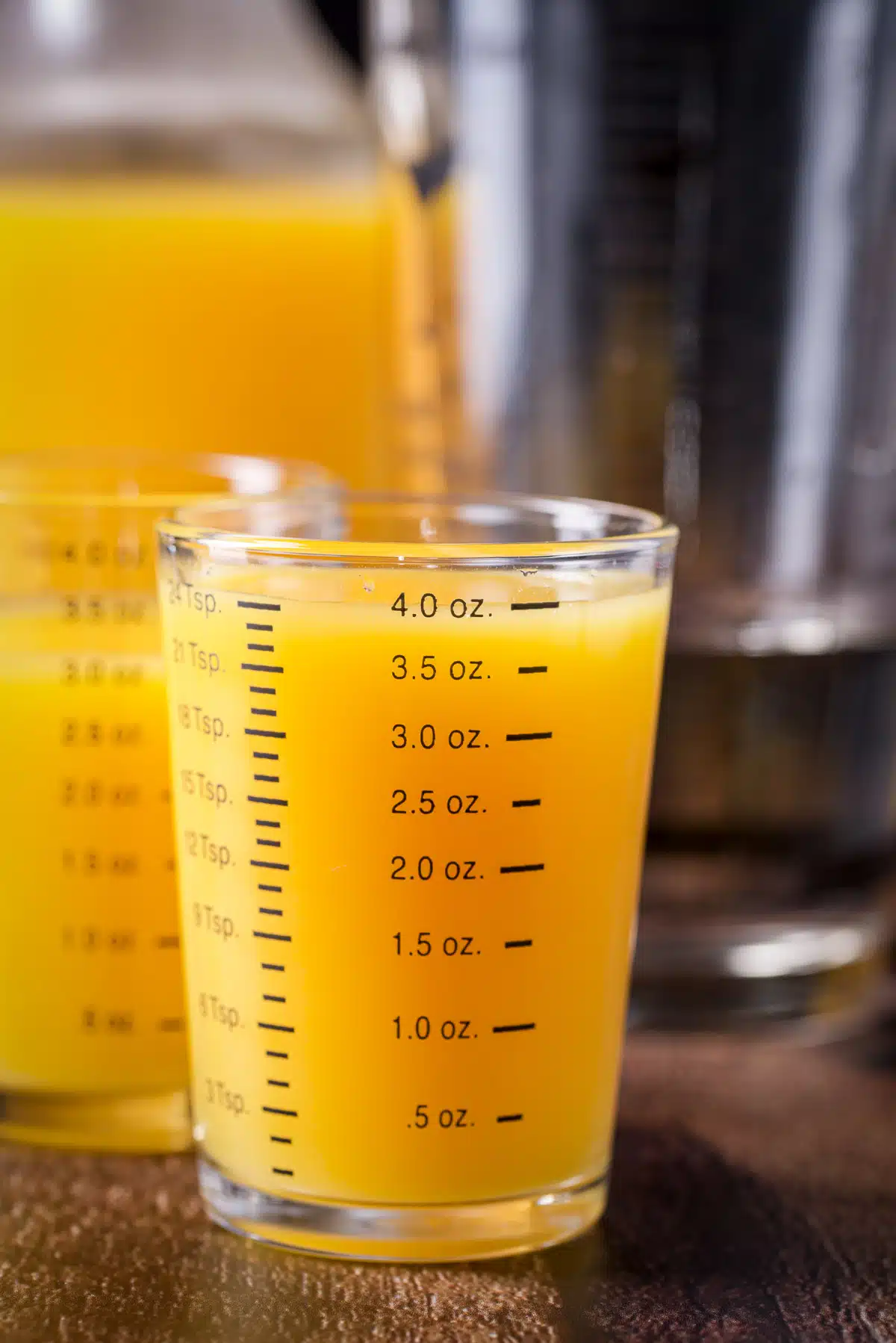 Orange juice measured out with the bottle behind