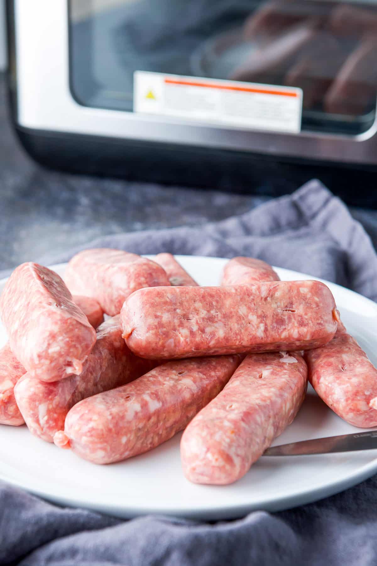 A knife on a plate with sausages with slits in them
