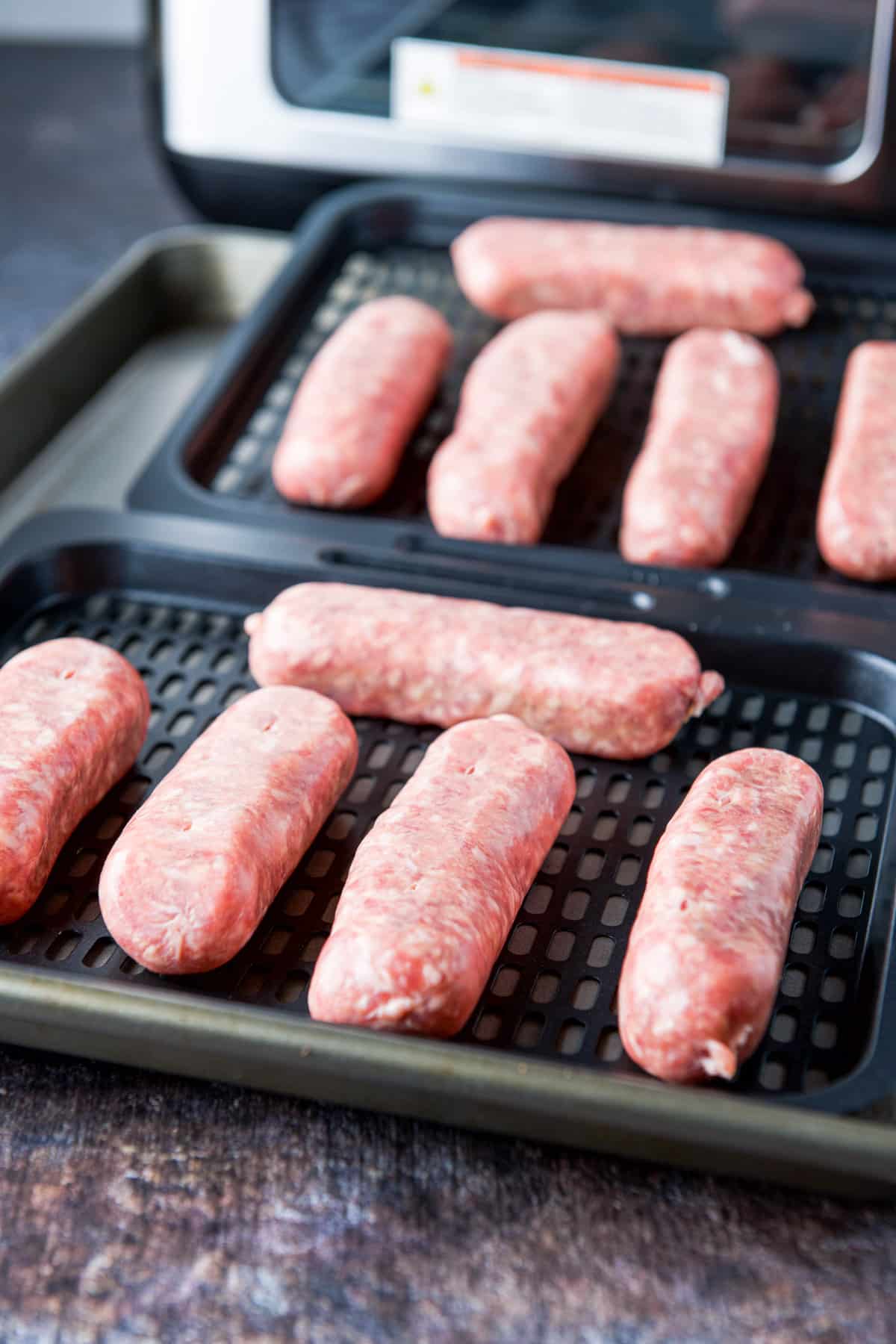 Two trays with raw sausages on them