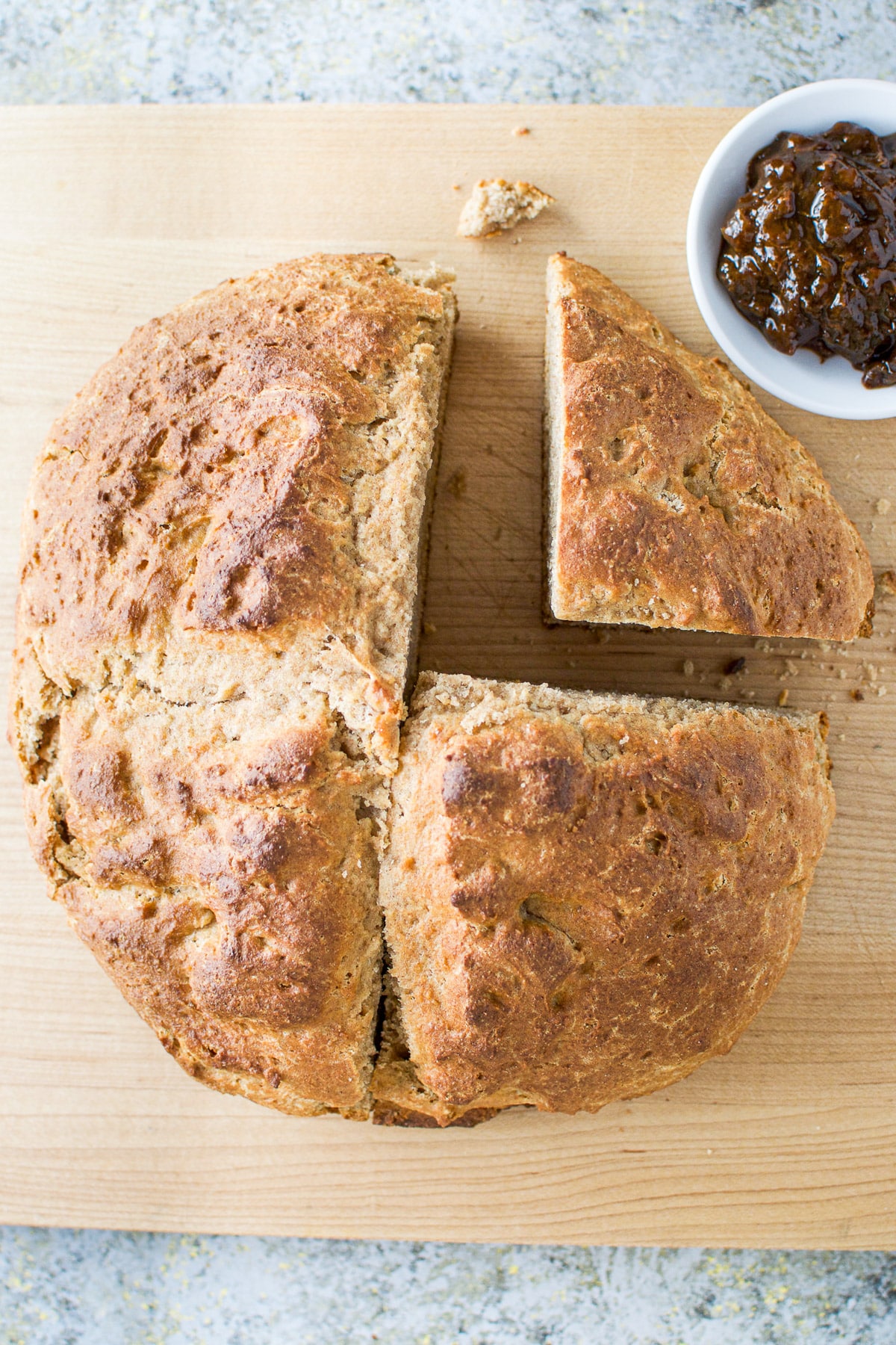 A round bread with two quarters cut out of it on a wooden board