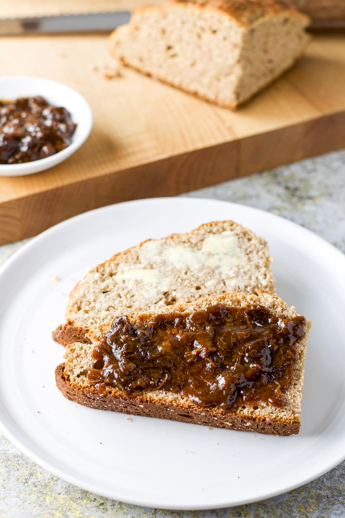 White plate with two pieces of bread slathered with butter and jam