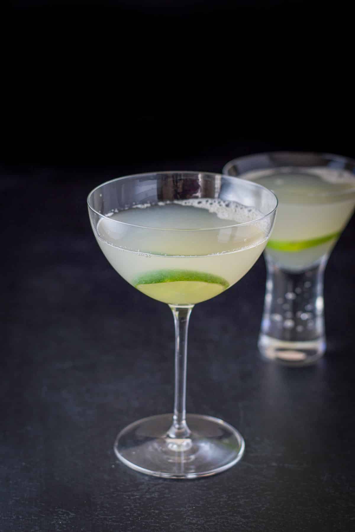 Bowl glass in front of a short glass filled with the lime cocktail