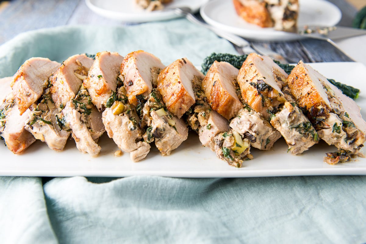 A white platter with sliced up pork loin - horizontal