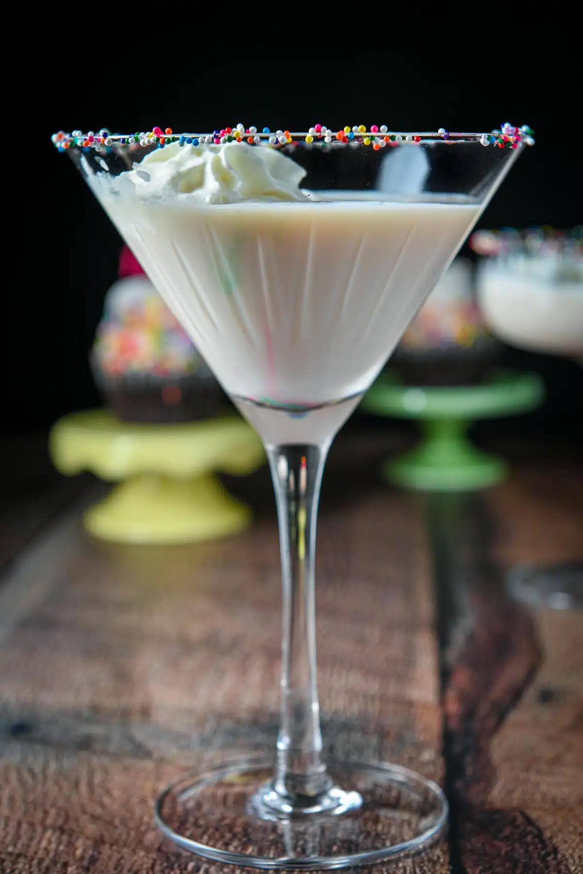 Close view of a martini view filled with the cream drink with whipped cream and colorful balls