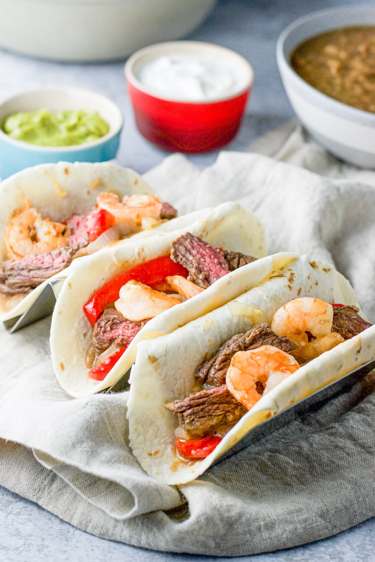 close up of three tacos with shrimp, beef and veggies