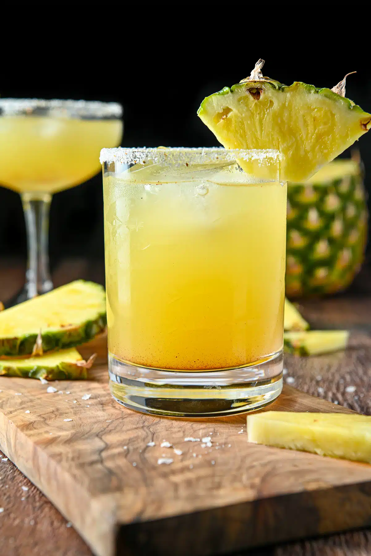 close vertical view of the pineapple margaritas with salted and garnished rims