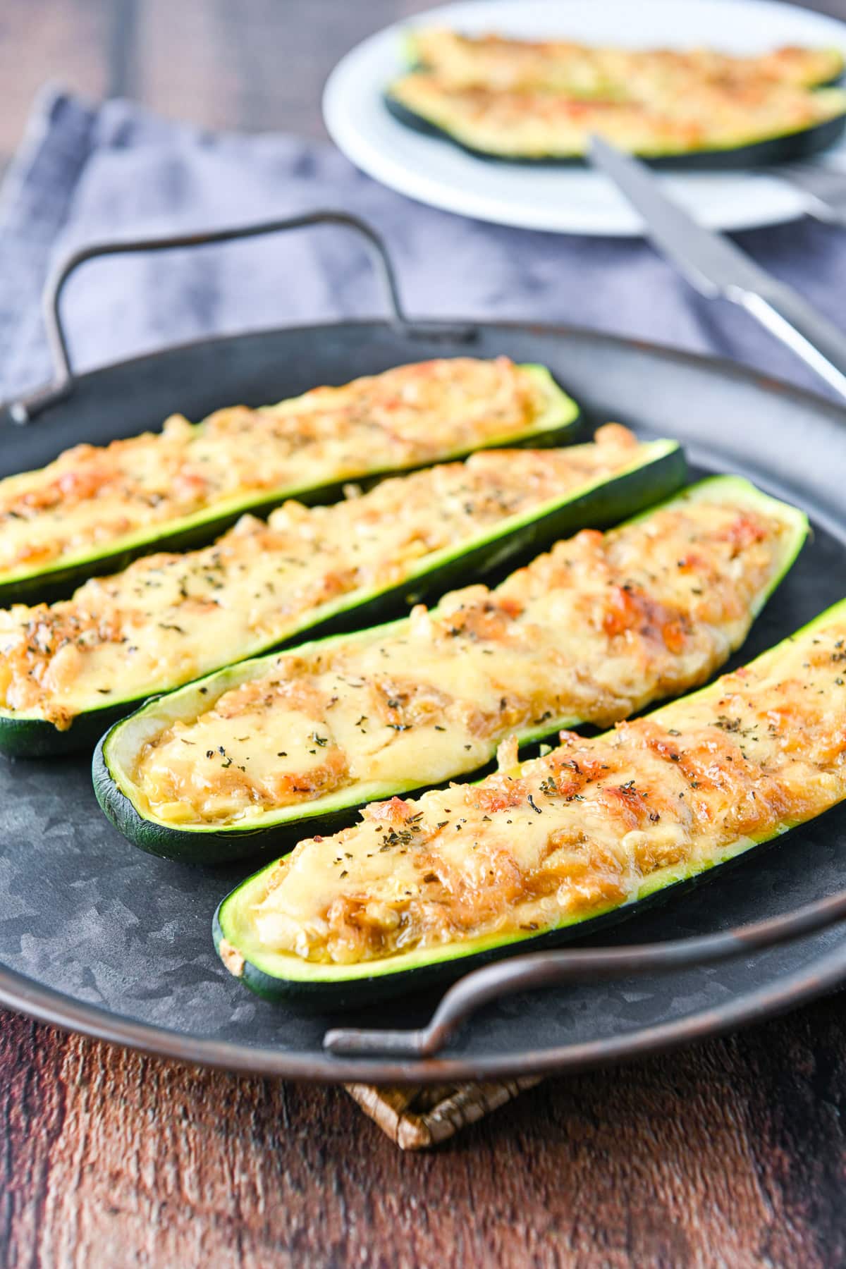 A metal round tray with the stuffed vegetable on it with a plate in the back with two more halves
