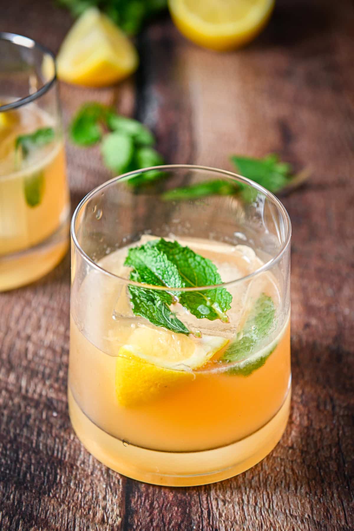 Close up of a glass with the smash cocktail in it with mint and lemon