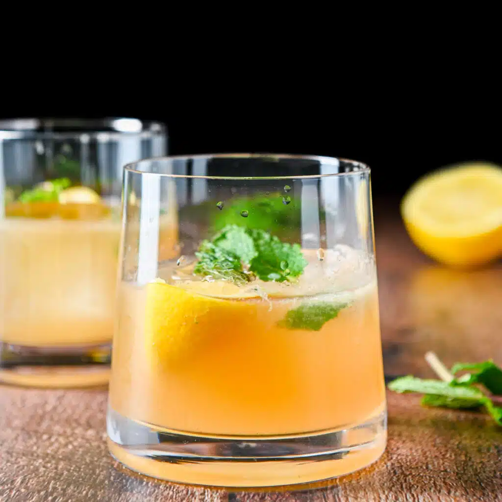 square photo of the two glasses with the amber drink with mint and lemon