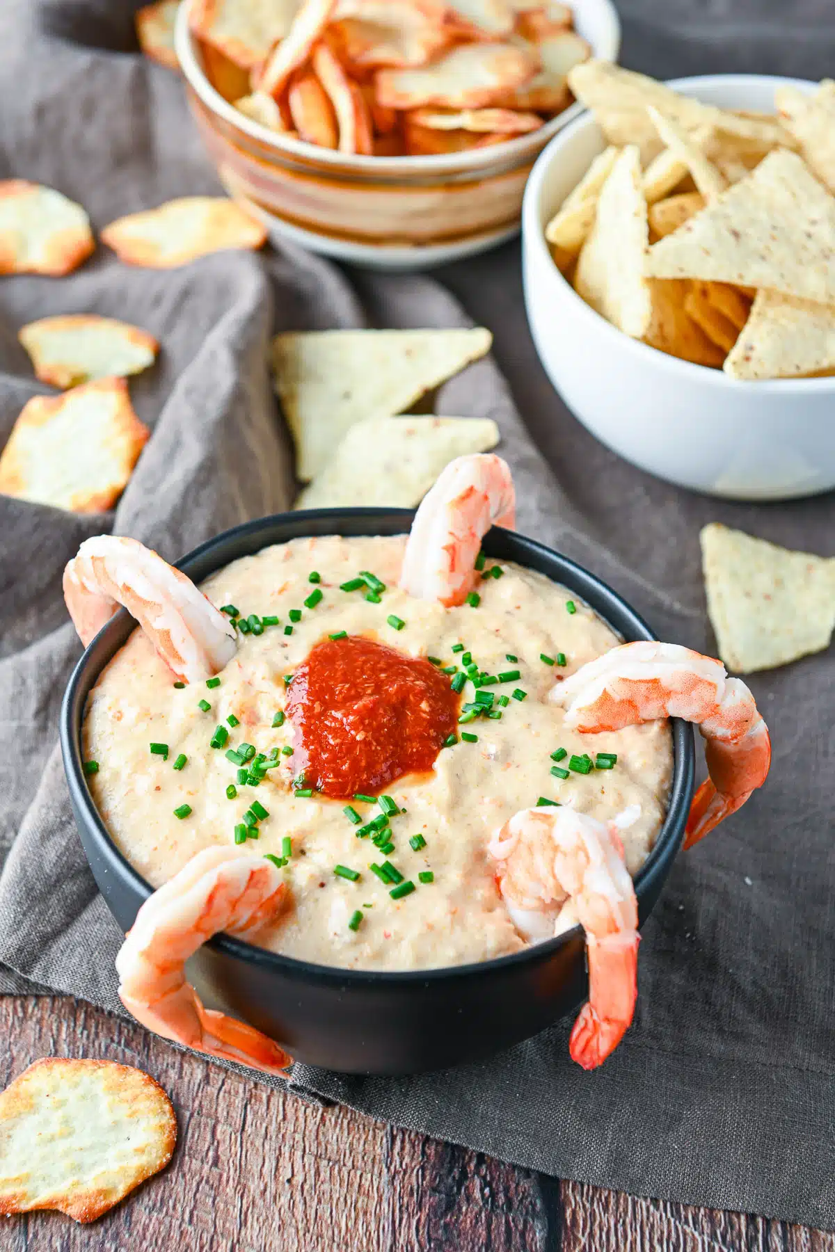 Chips in bowls with some on the table with the shrimp dip in front