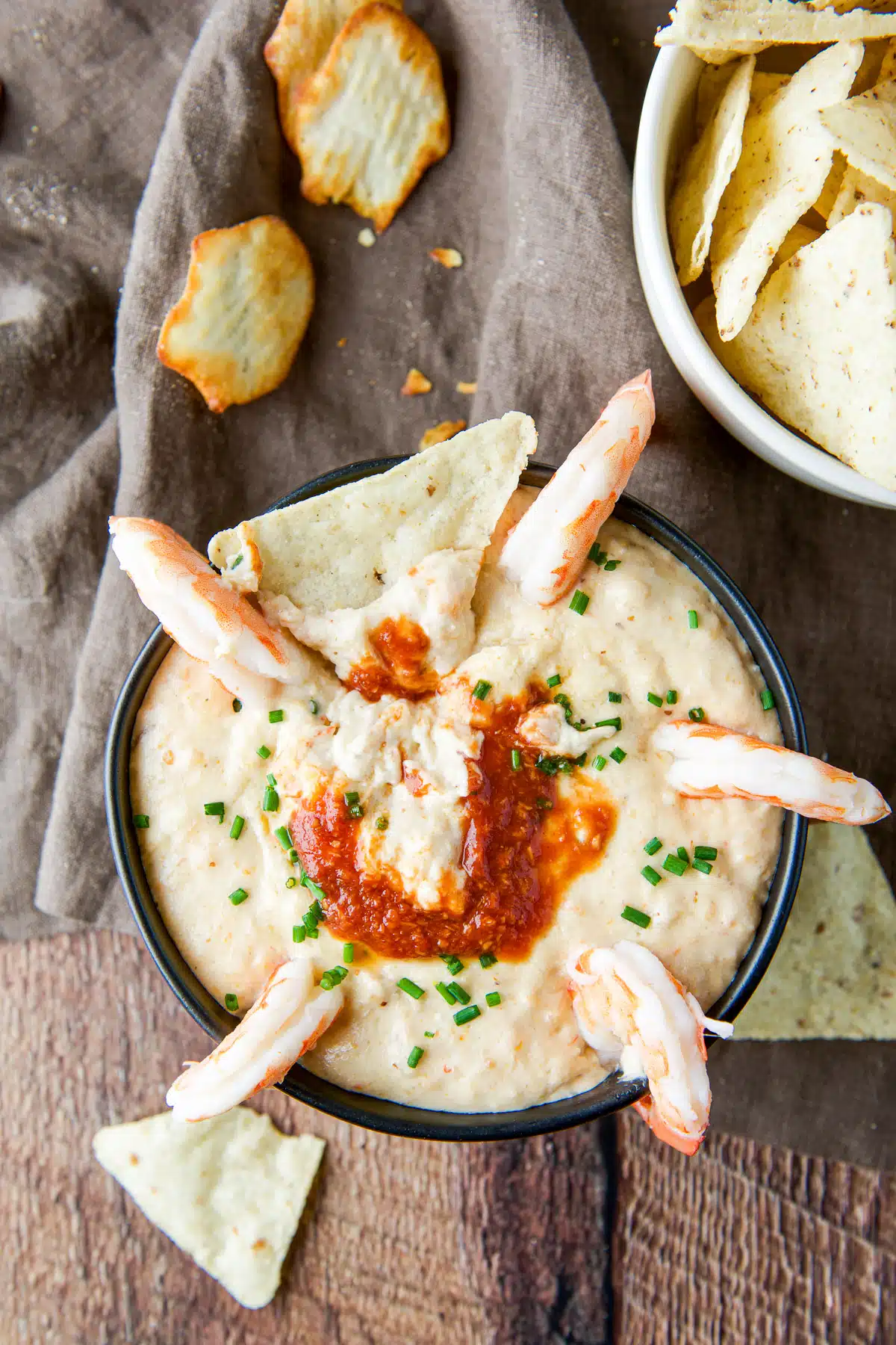 Overhead view of the dip with a chip in it, shrimp on the edges and sauce in the middle
