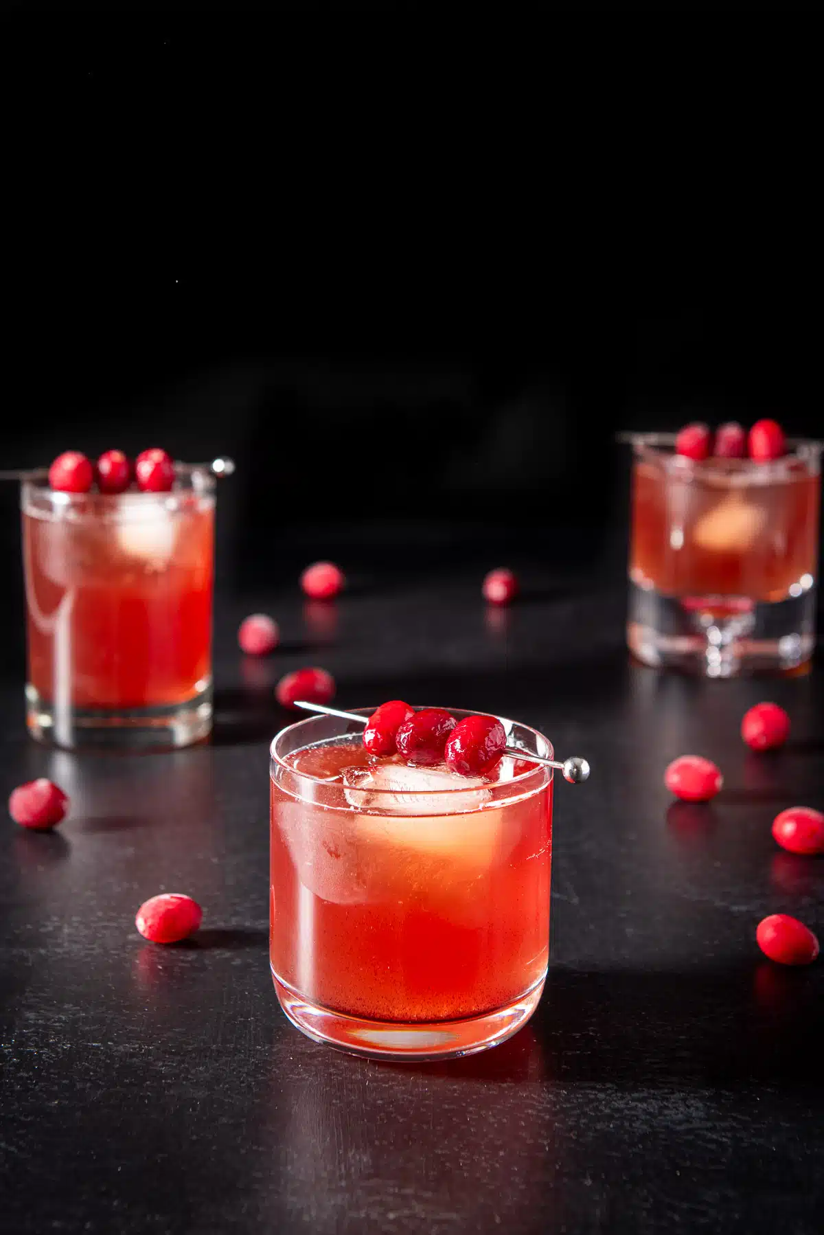 Closer view of the cranberry cocktail with cranberries on skewers and on the table with the other drinks
