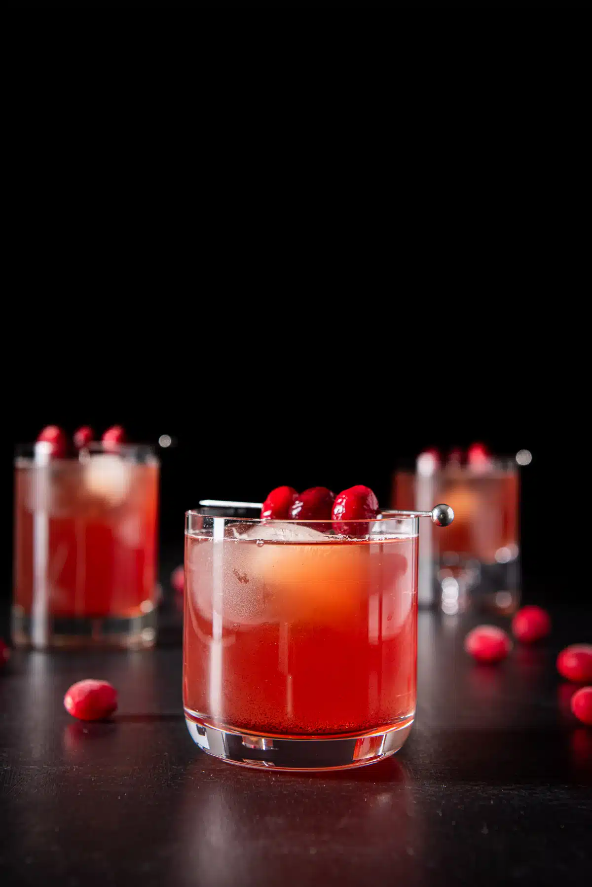 Vertical view of the bourbon cocktail with cranberries as garnish