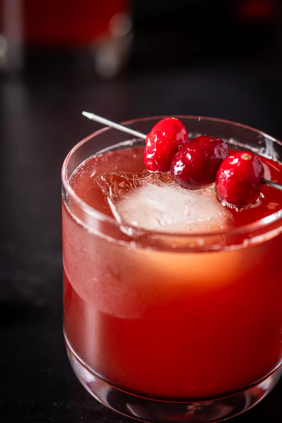 close up of the bourbon drink in a glass with cranberries on a martini pick