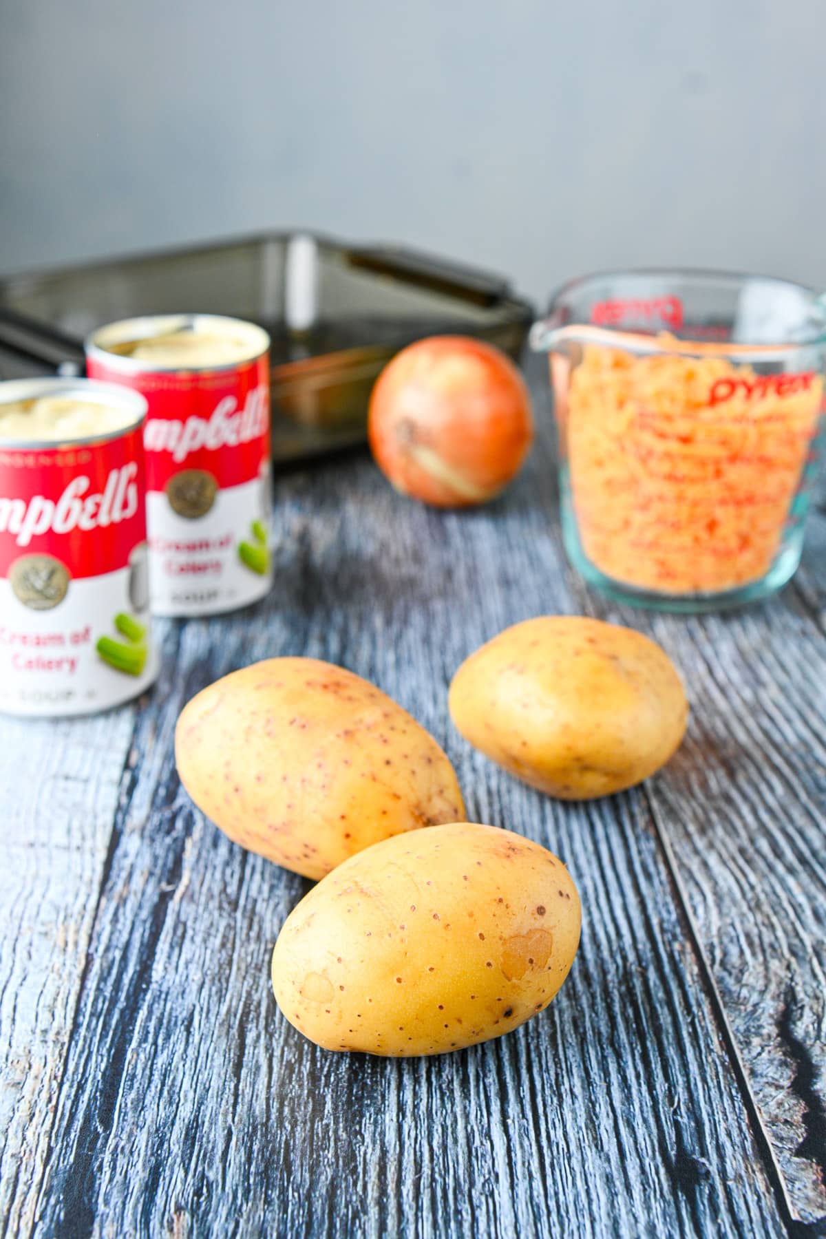 Potatoes, canned soup, cheese and an onion on the table