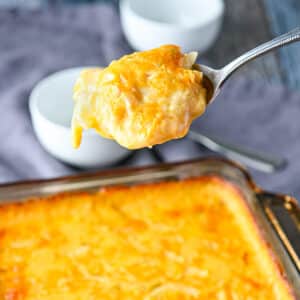 Square photo of a spoon with the potatoes on it held over the casserole dish