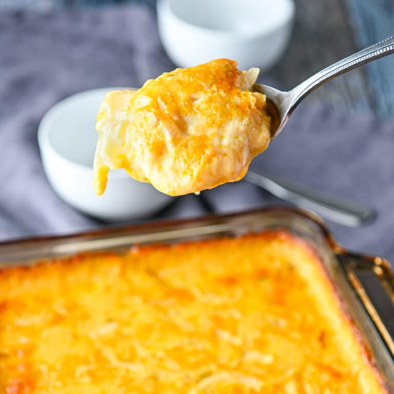 Square photo of a spoon with the potatoes on it held over the casserole dish