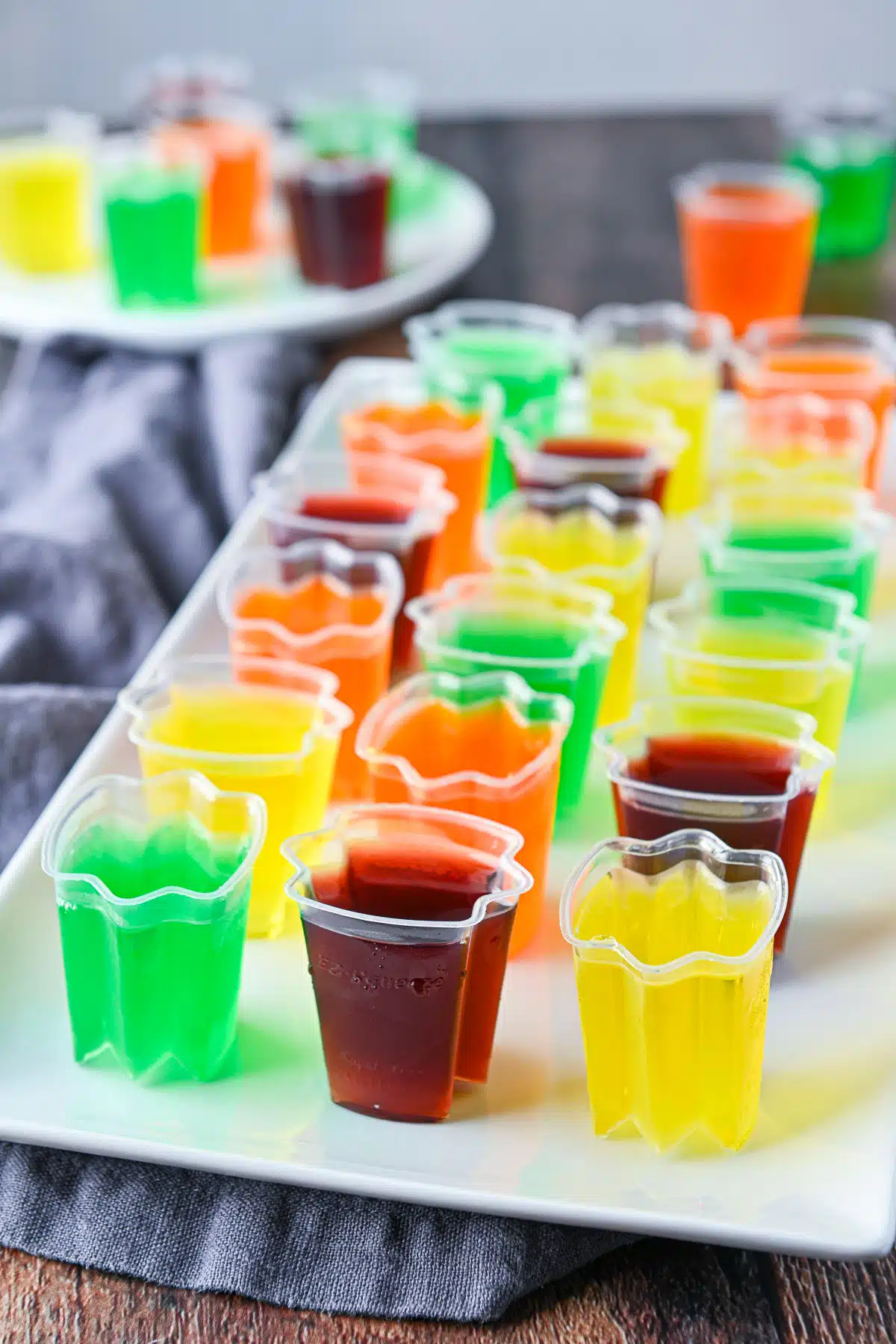 A rectangle platter with red, green, yellow, and orange jello in cups