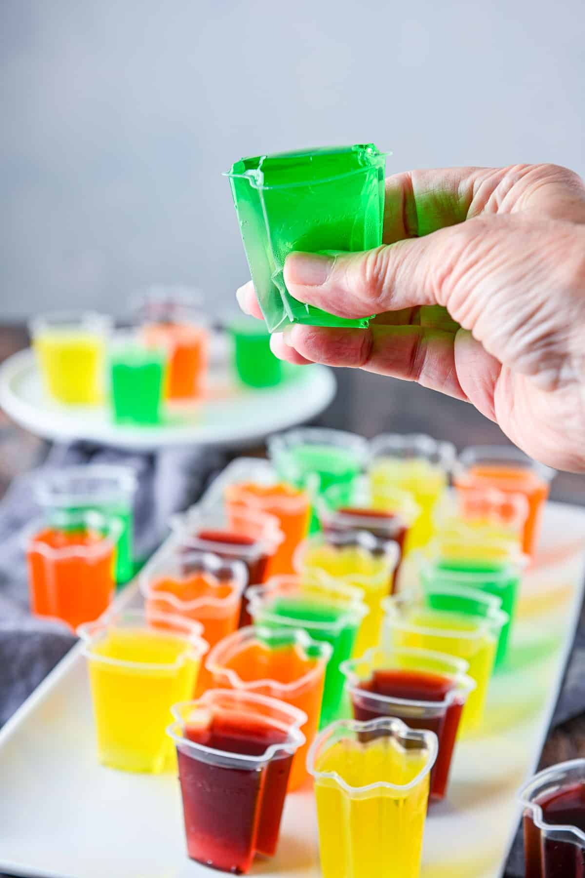 A hand holding a jello cup and squeezing it to get the jello out
