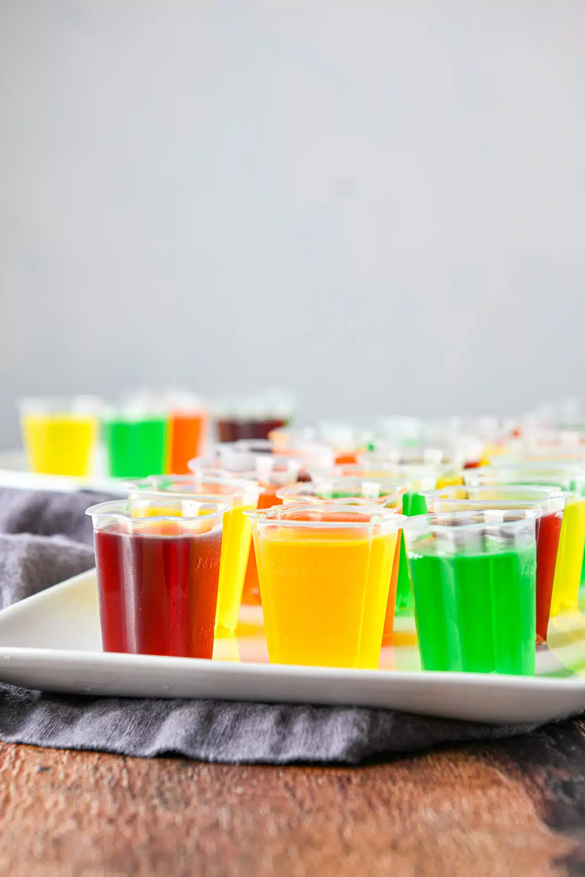 Vertical view of jello shots in cups on a white platter