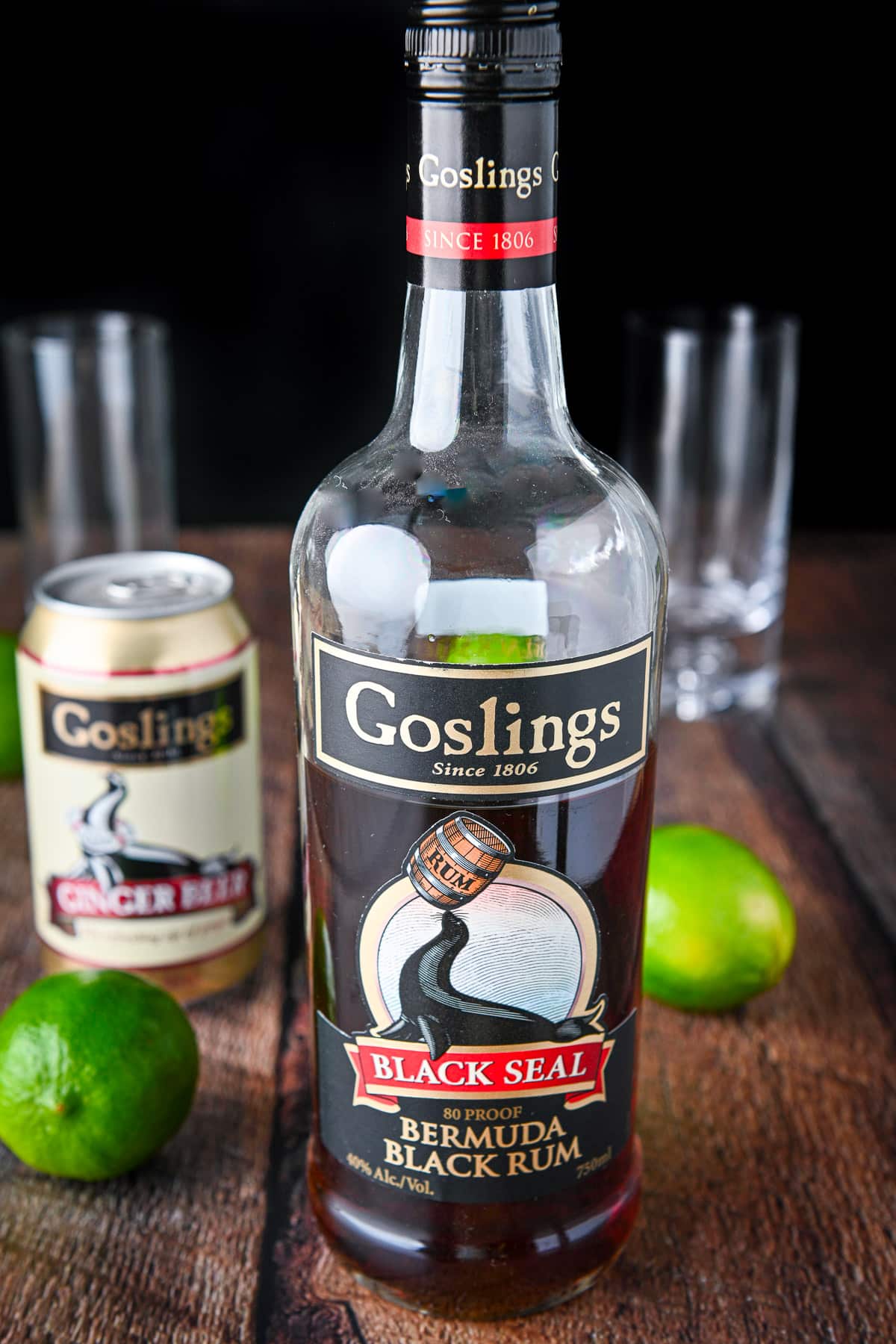 Dark rum, limes, and ginger beer on a wooden table