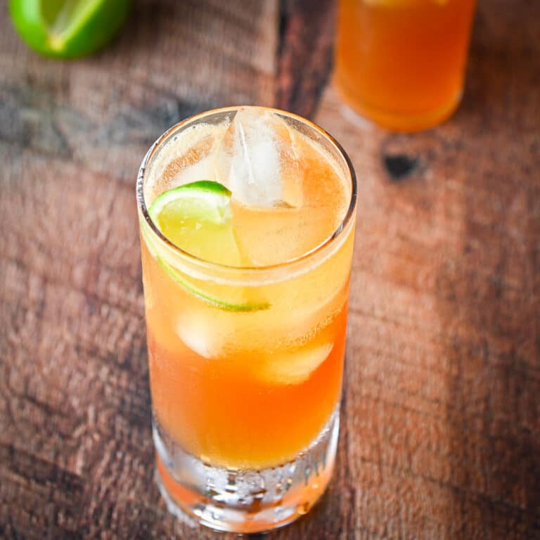 square view of a tall glass with the cocktail in it along with a lime for garnish