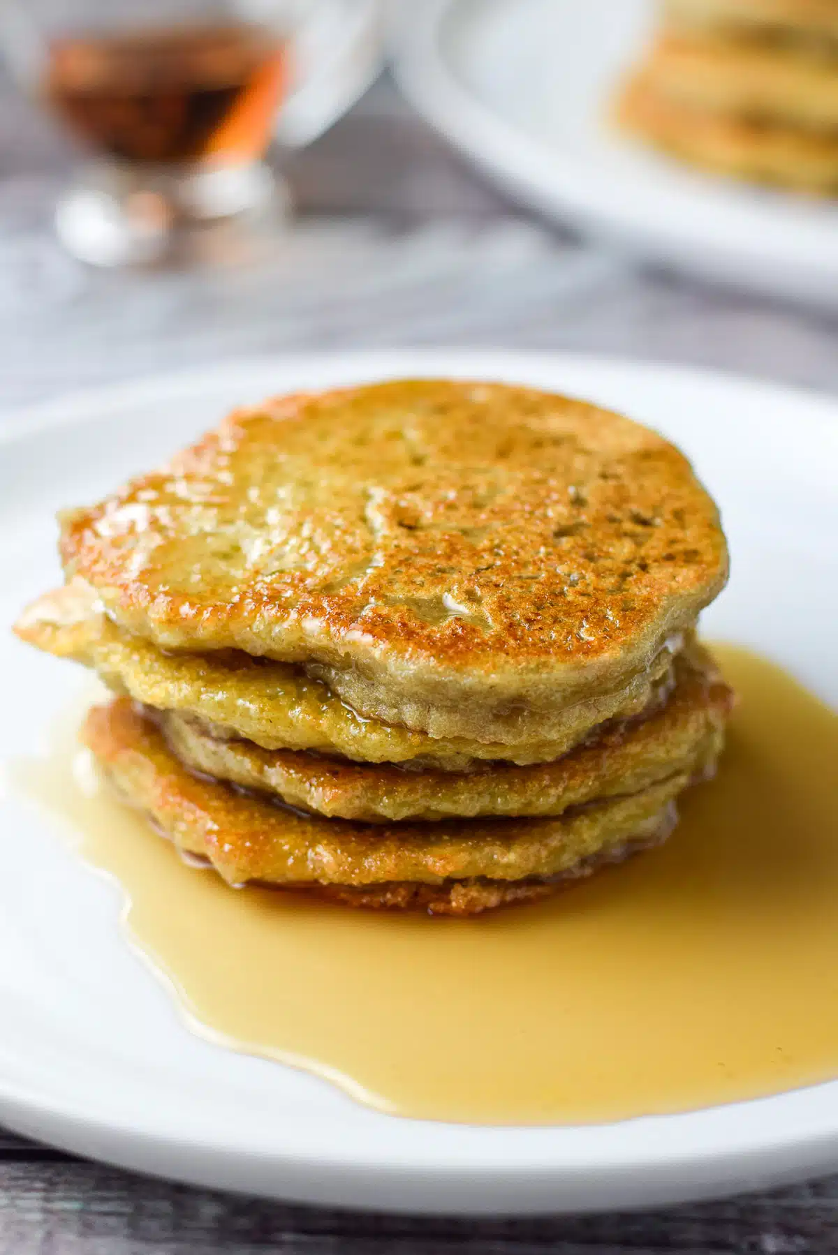 close up of four pancakes on a plate with syrup