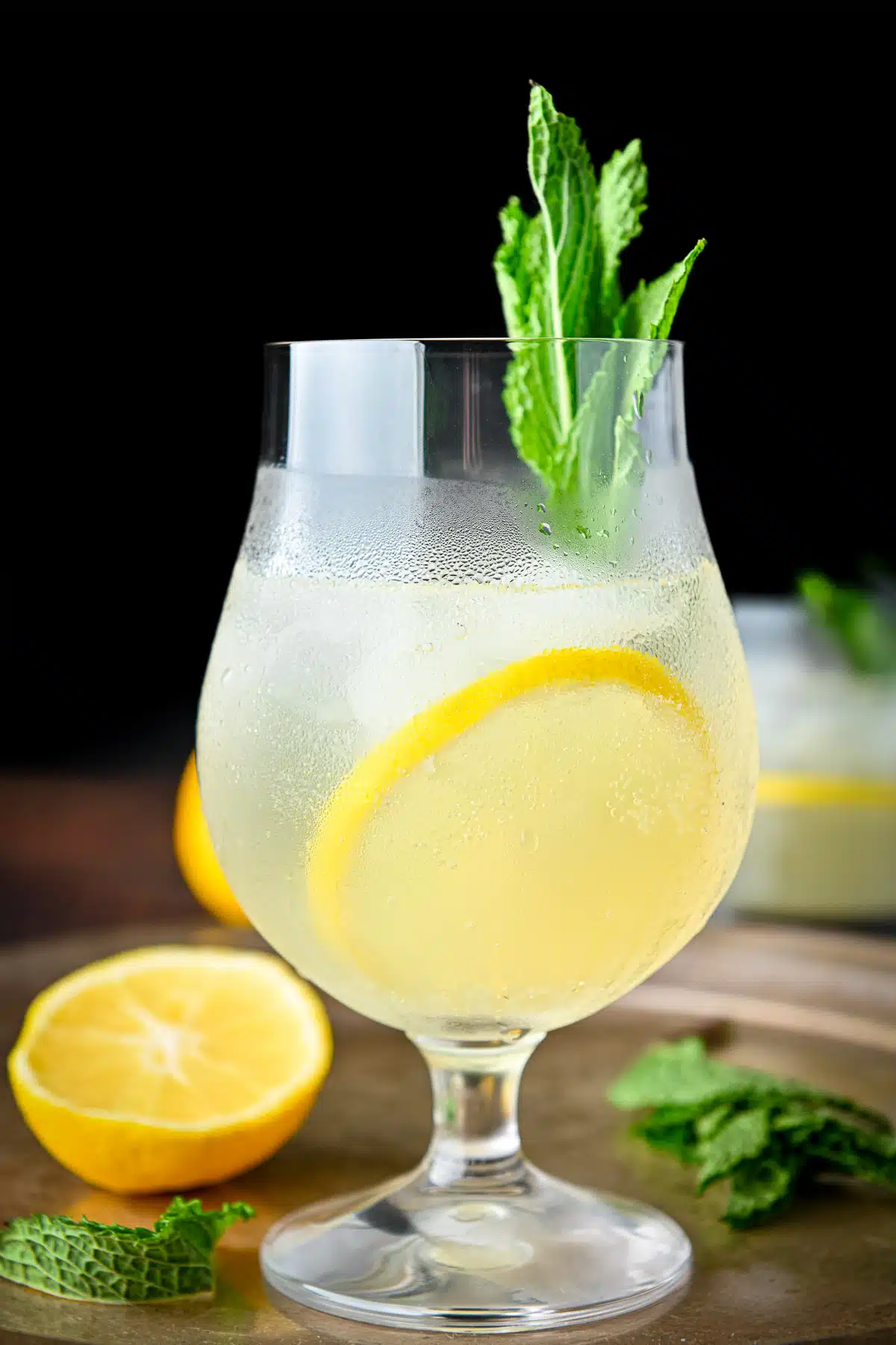 Vertical view of the limoncello spritz on a tray with lemon and mint